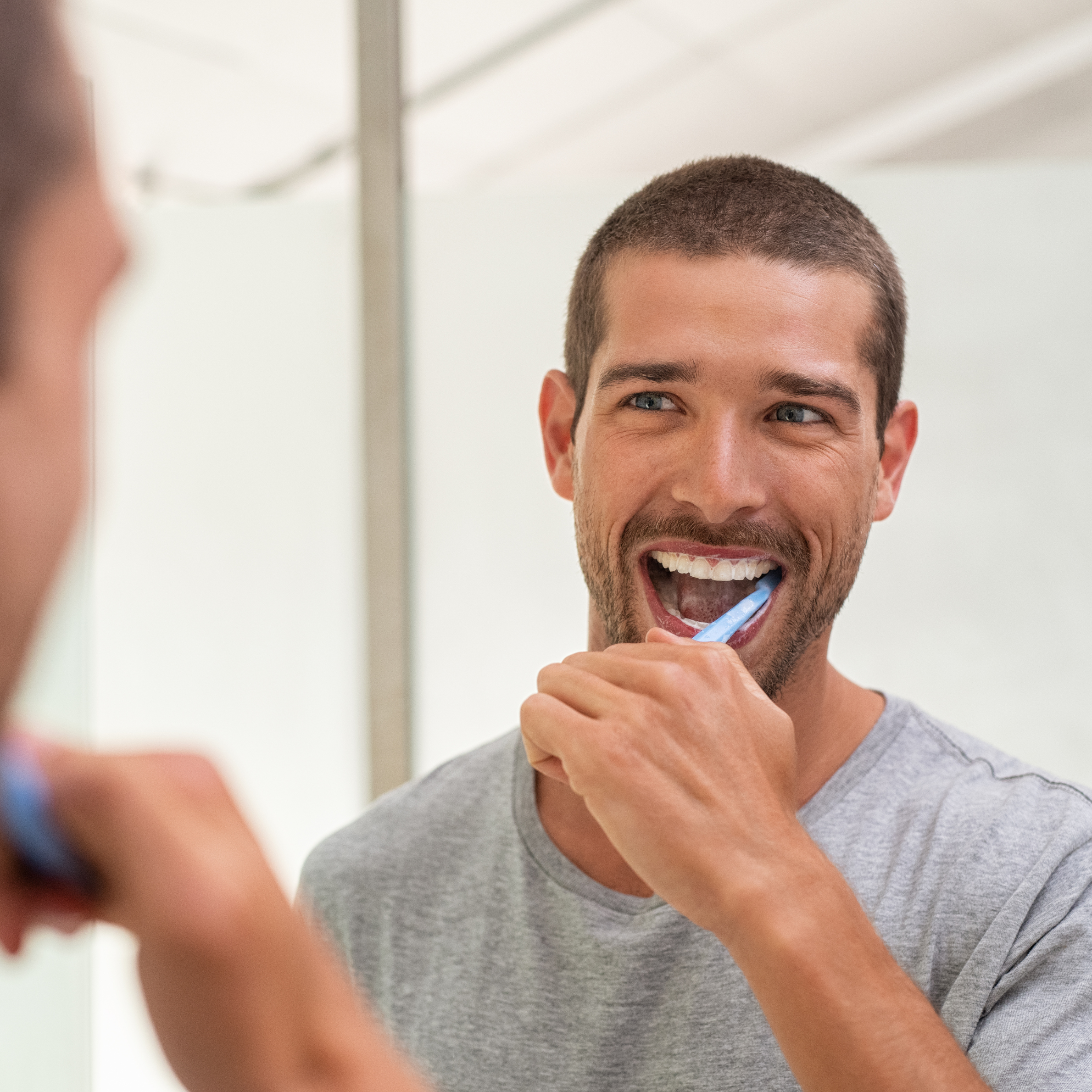 Man brushing his teeth in a mirror